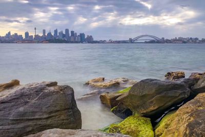 Scenic view of sea and buildings against cloudy sky