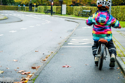 Rear view of man riding bicycle on road