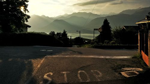 Road by trees and mountains against sky