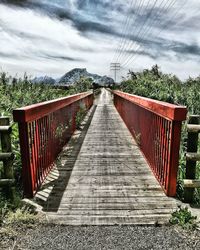 Footbridge amidst trees against sky