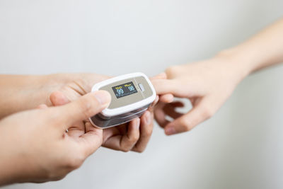 Close-up of hand holding camera over white background