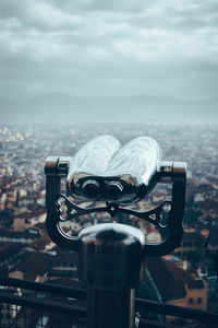 Close-up of coin-operated binoculars against cityscape