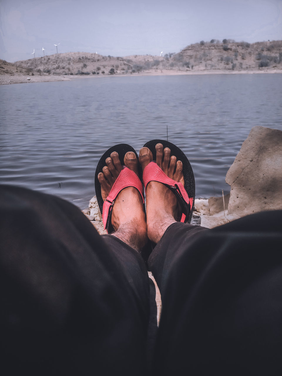 LOW SECTION OF WOMAN RELAXING AT SEA SHORE