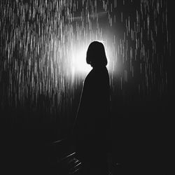 Silhouette woman standing in water at night