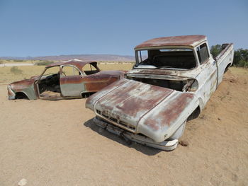 Abandoned vintage car on field against sky