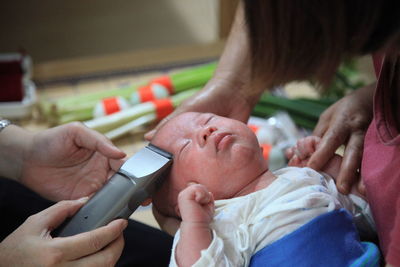 Cropped hands shaving baby head