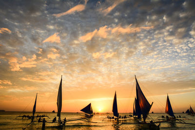 Sailboat on sea against cloudy sky during sunset