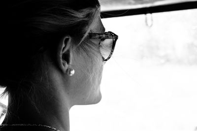 Rear view of young woman looking through wet windshield while traveling in car