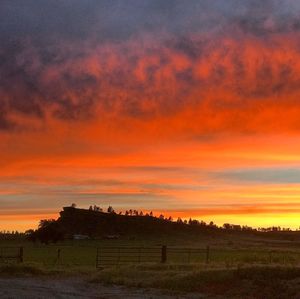 Scenic view of silhouette field against orange sky