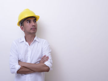 Young man looking away while standing against white background