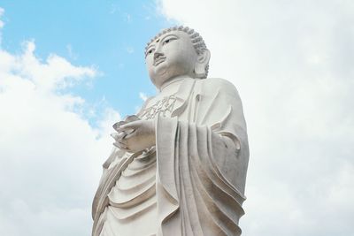 Low angle view of buddha statue against sky