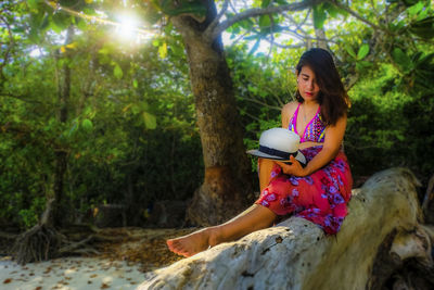 Young woman sitting on tree trunk