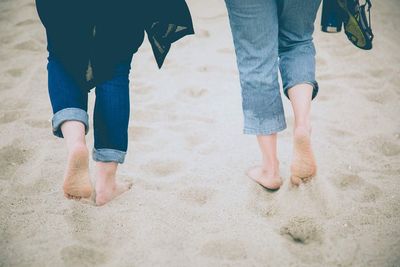 Low section of two persons walking on beach