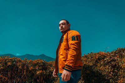 Young man looking away against blue sky