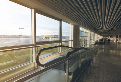 Escalator inside international airport terminal on blurred passenger walking in the airport. 