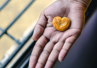 A girl holding on to a heart shaped cookie