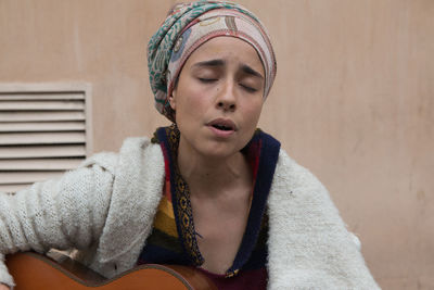 Close-up portrait of young woman playing guitar