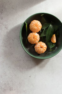 High angle view of fruits and leaves in bowl on table