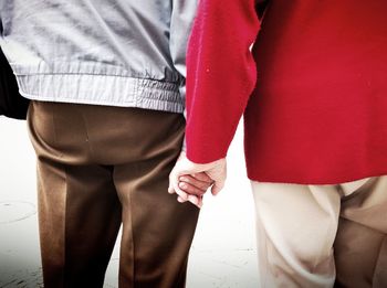 Rear view of senior couple holding hands on street
