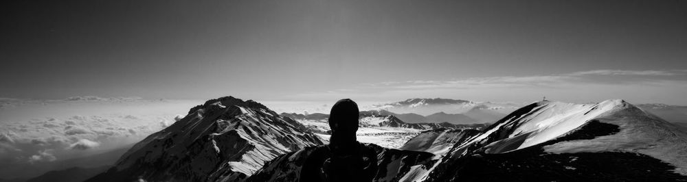 Rear view of woman with arms outstretched on snowcapped mountain