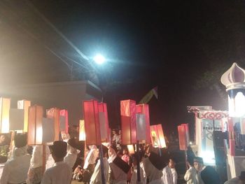 Group of people at illuminated street lights at night