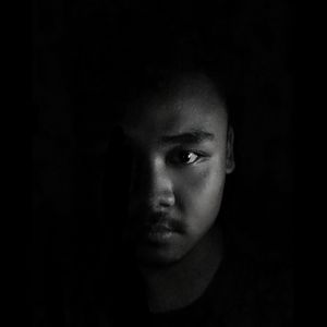 Close-up portrait of young man against black background