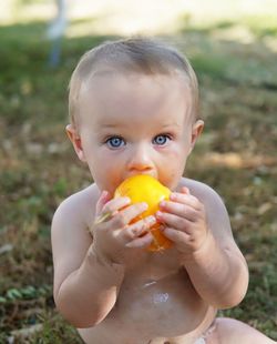 Blue eyed boy biting into juicy, fresh, homegrown lemon boy tomato on a summer day.