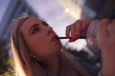 Close-up of beautiful young woman having drink in city