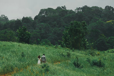 Rear view of people on field against trees