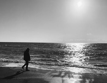 Man walking at beach against sky