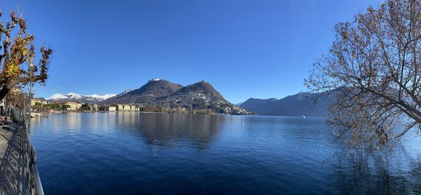 Scenic view of lake and mountains against clear blue sky