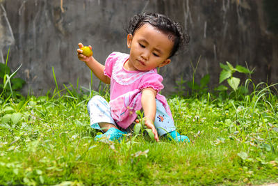 Cute baby girl sitting on grassy land