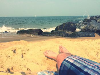 Low section of man relaxing on beach