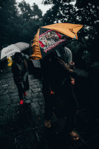 People walking on wet umbrella during rainy season