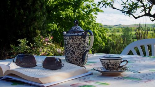 Coffee cup on table against trees