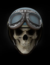 Close-up of human skull wearing helmet against black background