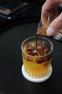 Midsection of person pouring drink in glass