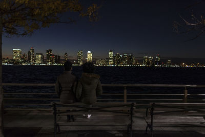 Two young women sitting on a park bench at the waterfront