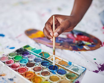 Cropped hand of woman painting on table