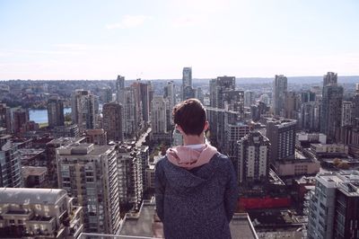 Rear view of modern cityscape against sky