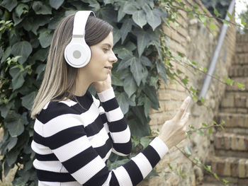 Young woman standing against plants