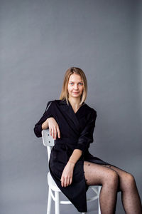 Portrait of young woman standing against wall