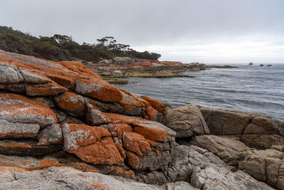 Scenic view of rocks by sea against sky