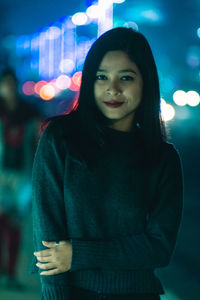 Portrait of smiling young woman standing at night