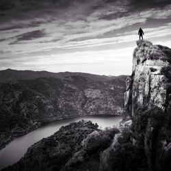 Man standing on cliff by sea