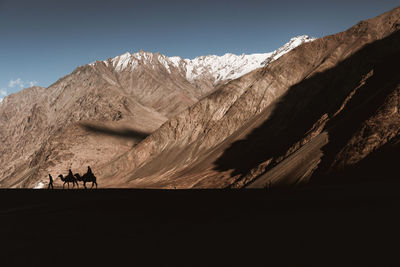 People riding camels against mountain