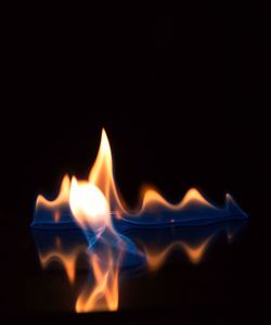 Close-up of burning candle against black background