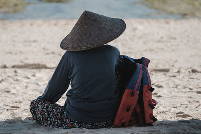 Rear view of woman sitting on sand at beach