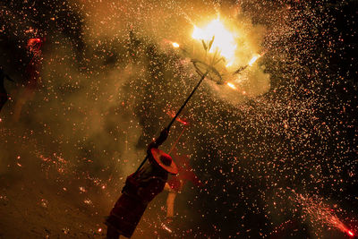 High angle view of man holding pole with fireworks at night