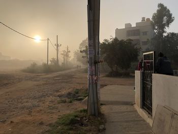 Street amidst buildings against sky during sunset